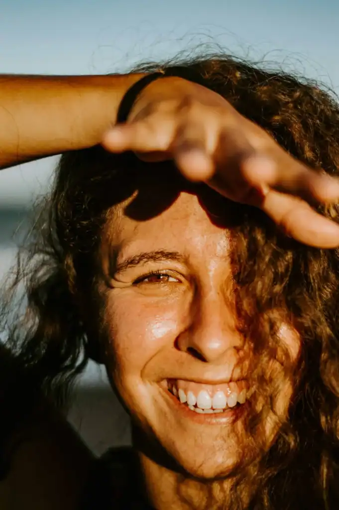 Femme souriante avec main sur le front, soleil naturel Témoignage Fabienne Hypnomagnet